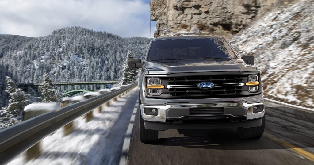 A Ford F-150 driving in a snowy, winter setting.