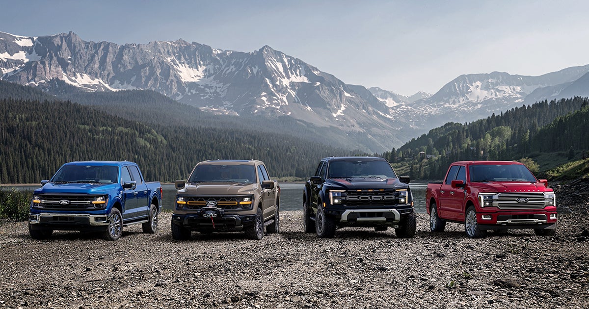 A lineup of Ford trucks against a mountain setting